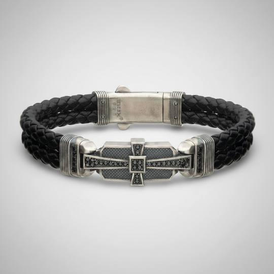 Double braid black leather bracelet with sterling silver cross on very light gray background