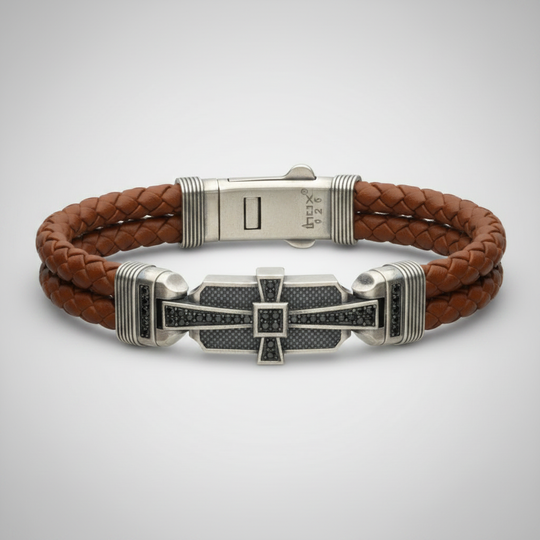 Brown braided leather bracelet with sterling silver cross on light gray background